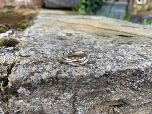 A triple-interlocking Russian wedding ring featuring two sterling silver bands and a 9ct yellow gold band.