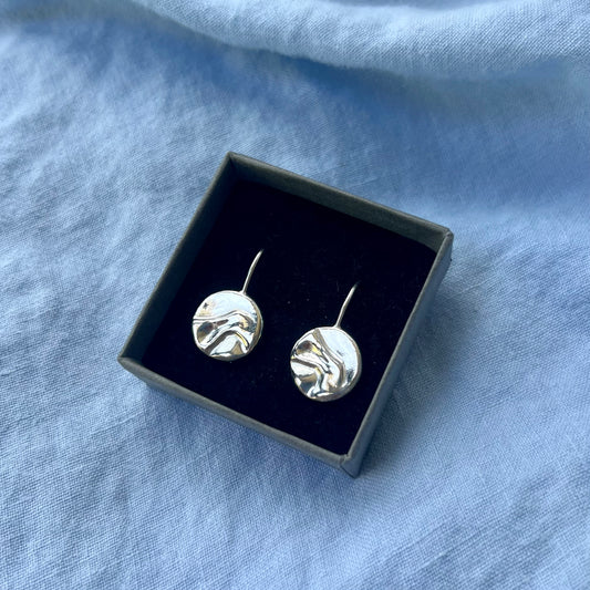 Sterling silver round drop pebble earrings in a black box on a blue background.
