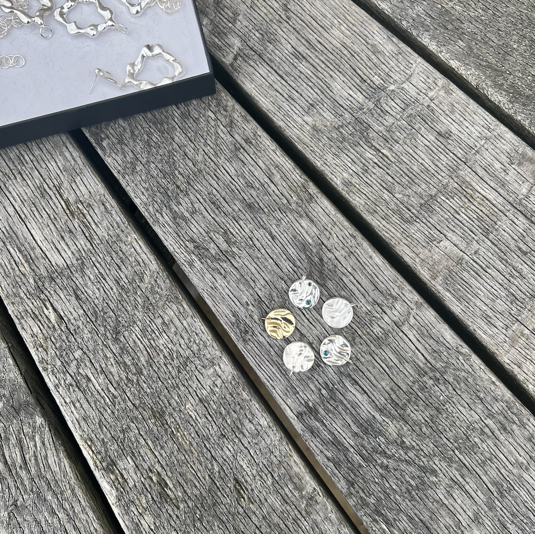 Five rock pool pendants in a circle on a wooden background.