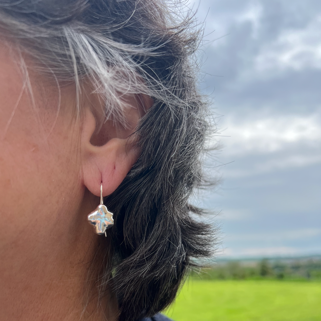 The sterling silver swirl drop earrings on a woman with short black hair.