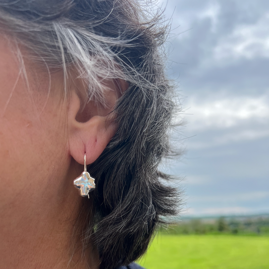 The sterling silver swirl drop earrings on a woman with short black hair.