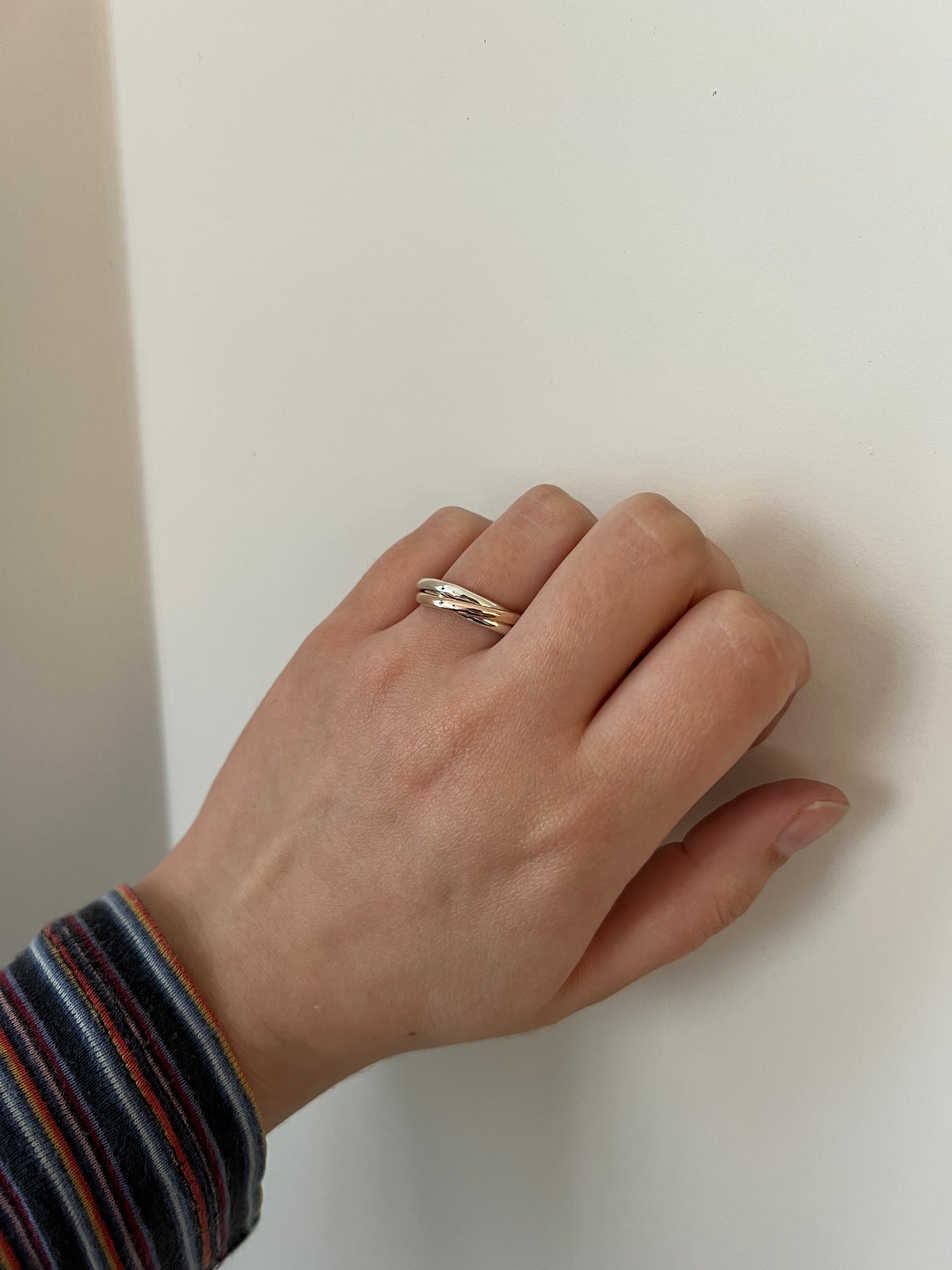 A triple-interlocking Russian wedding ring featuring two 9ct white gold bands and a 9ct rose gold band.