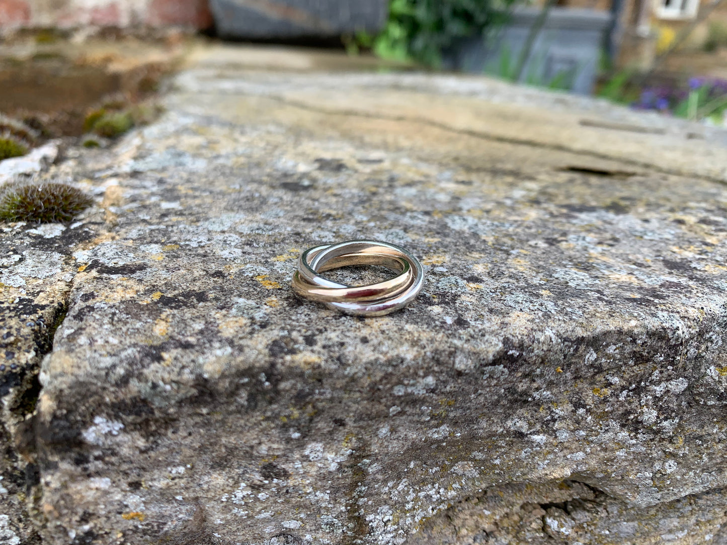 A triple-interlocking Russian wedding ring featuring two sterling silver bands and a 9ct yellow gold band.