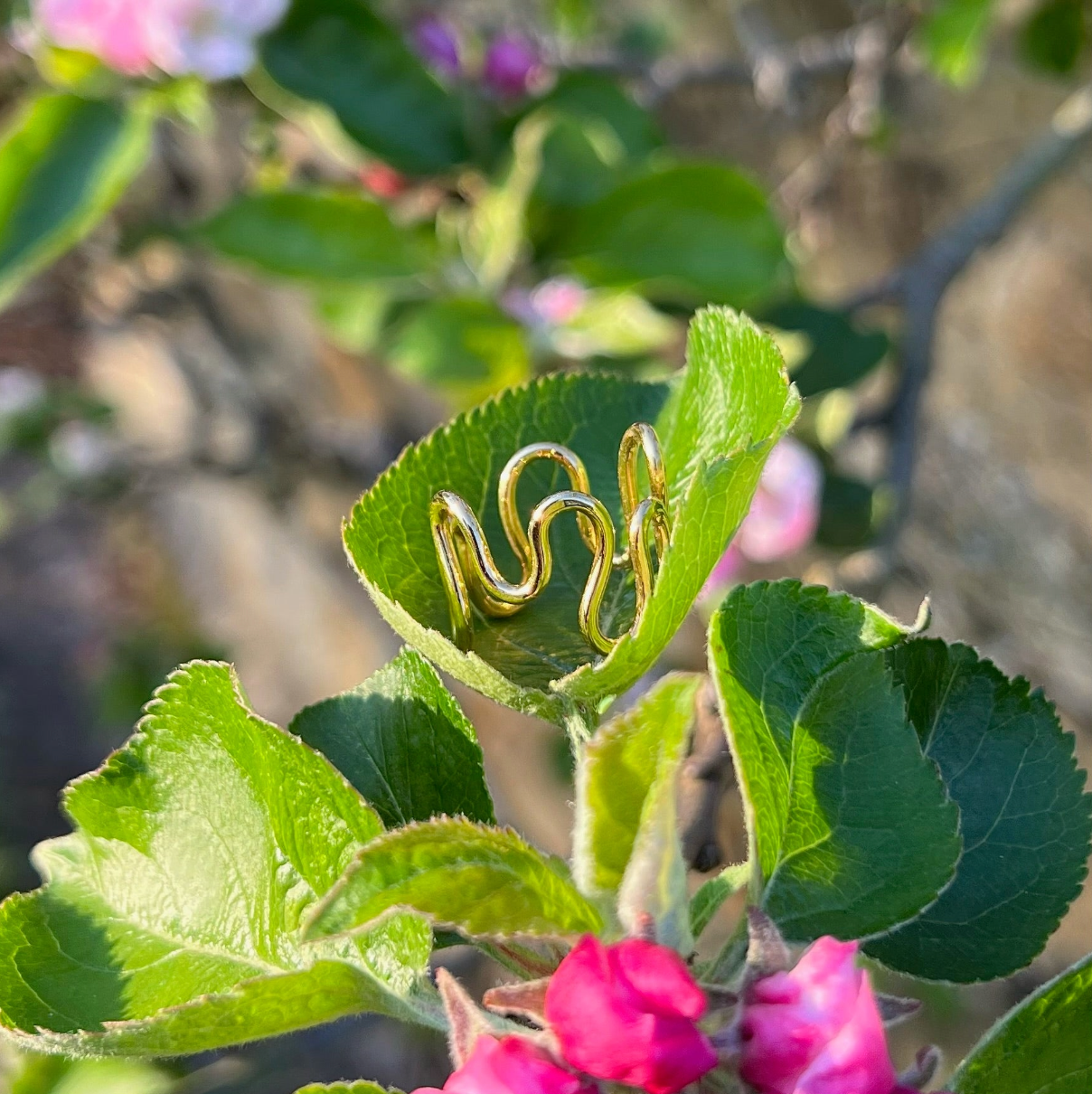 A gold vermeil ripple ring on a leaf.
